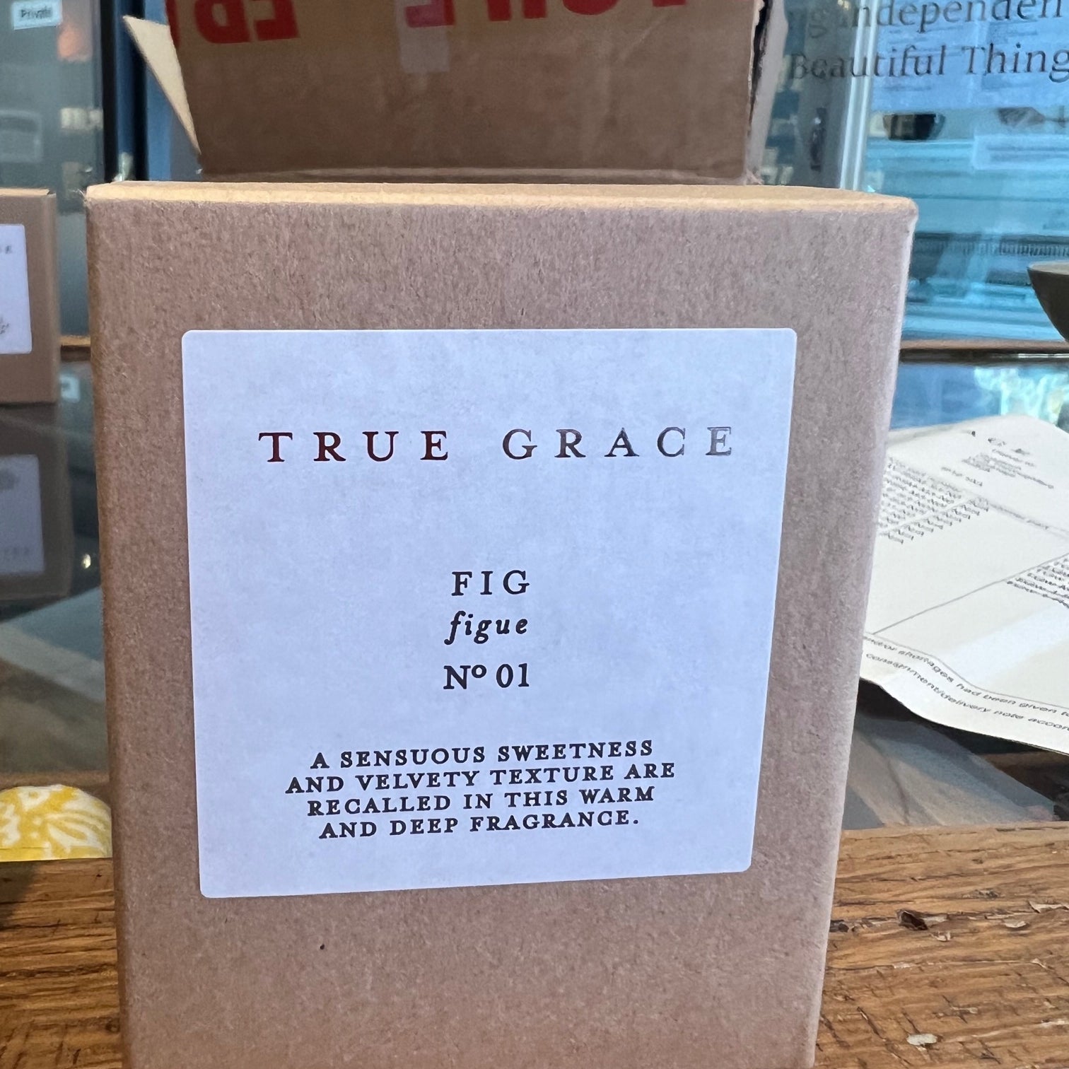 Box of 'True Grace Fig' candle with a label on a wooden surface