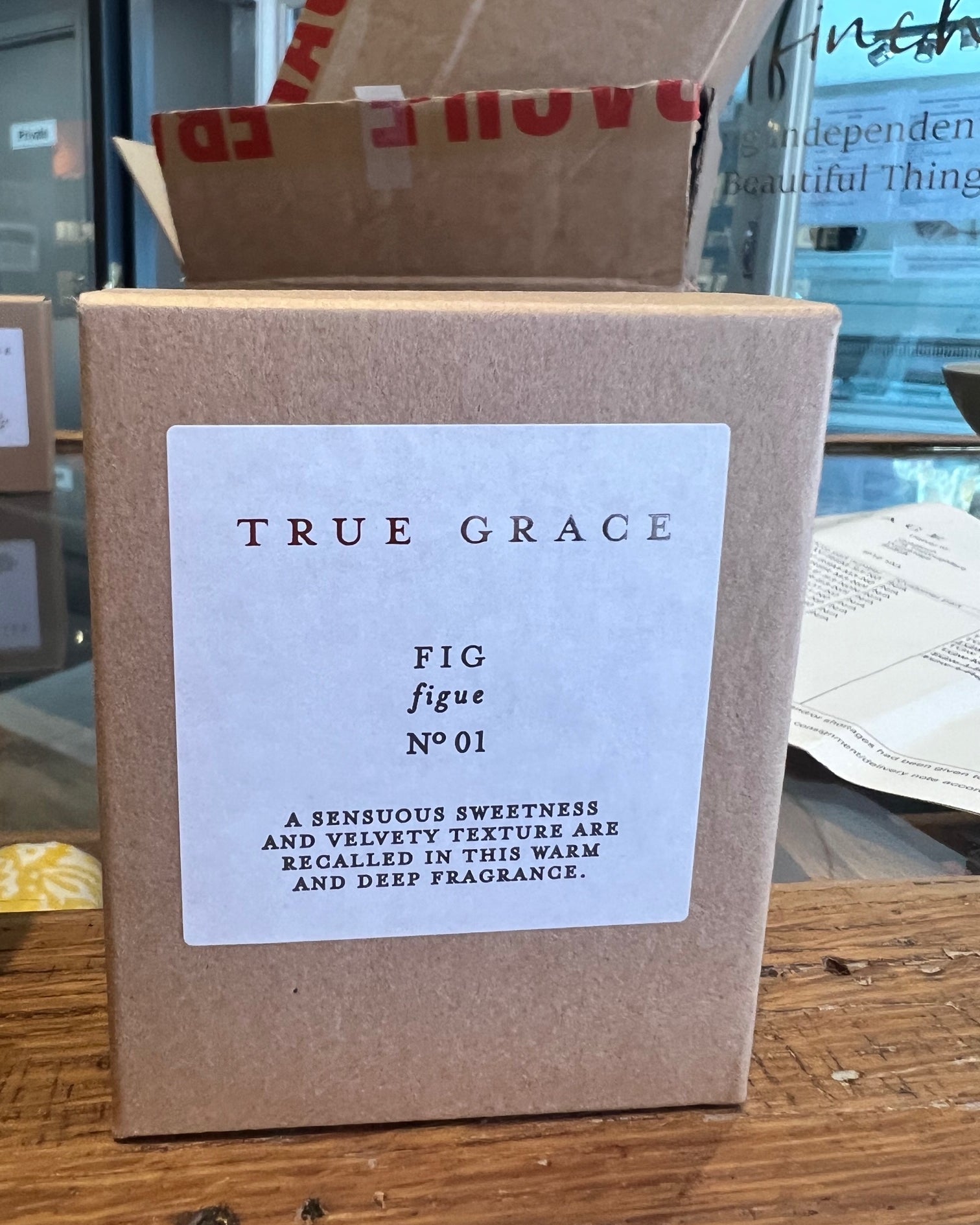 Box of 'True Grace Fig' candle with a label on a wooden surface