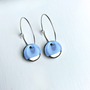 Pair of blue earrings with silver hooks on a light blue background