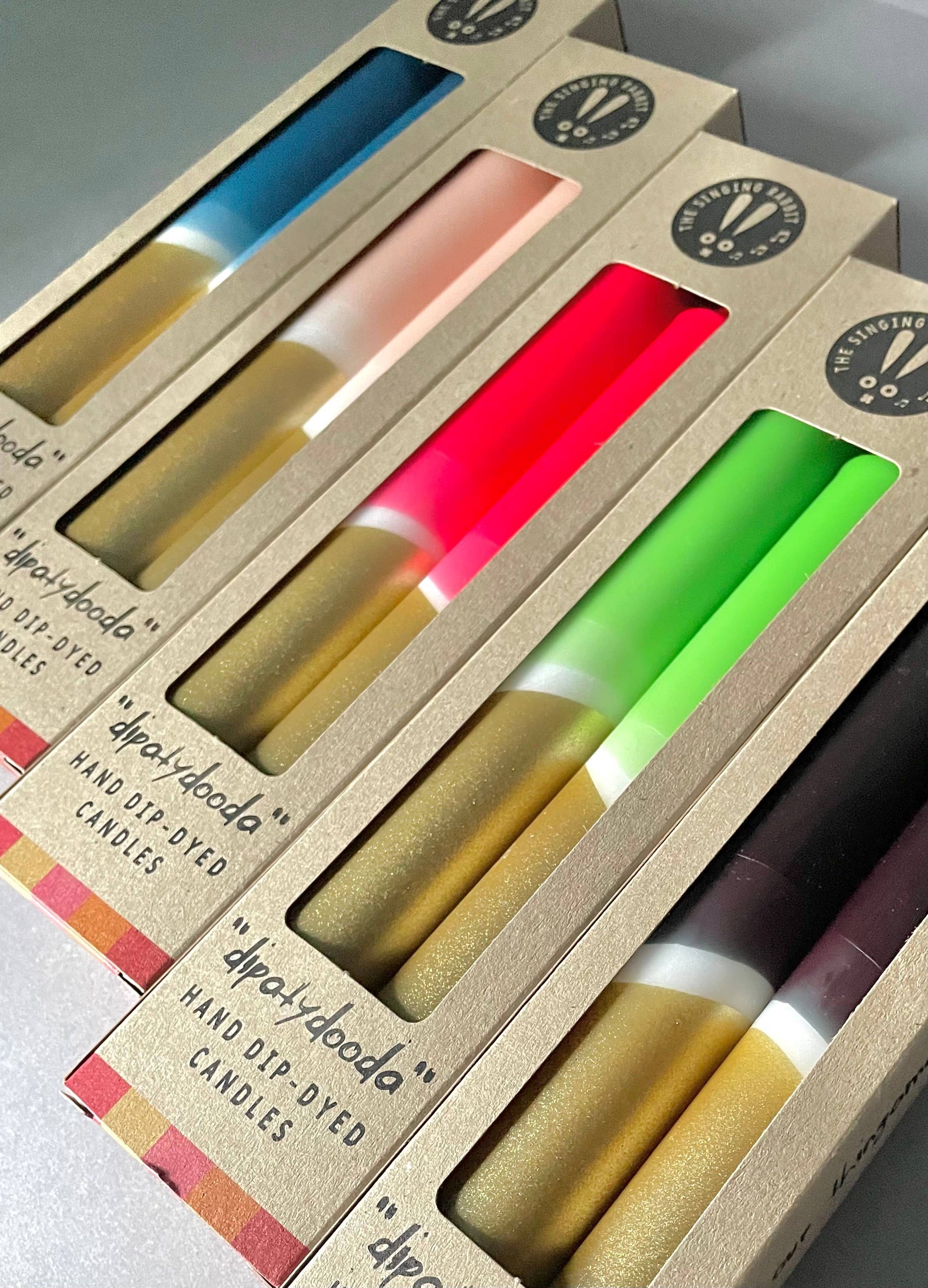 Packaged candles with colorful wicks in a cardboard box