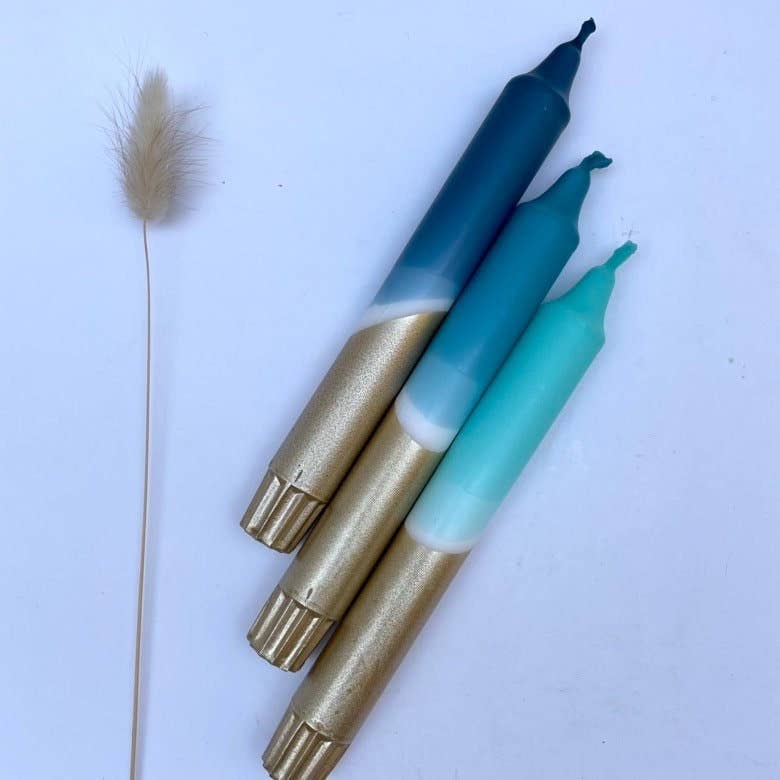 Three markers with gold bodies and blue, green, and teal tips on a light blue background.