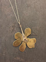 Gold flower-shaped pendant on a chain against a dark textured background