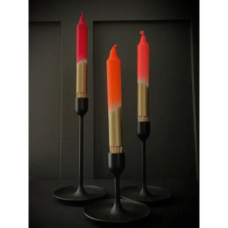 Three candles with red and gold gradient on black stands against a dark background