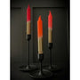 Three candles with red and gold gradient on black stands against a dark background