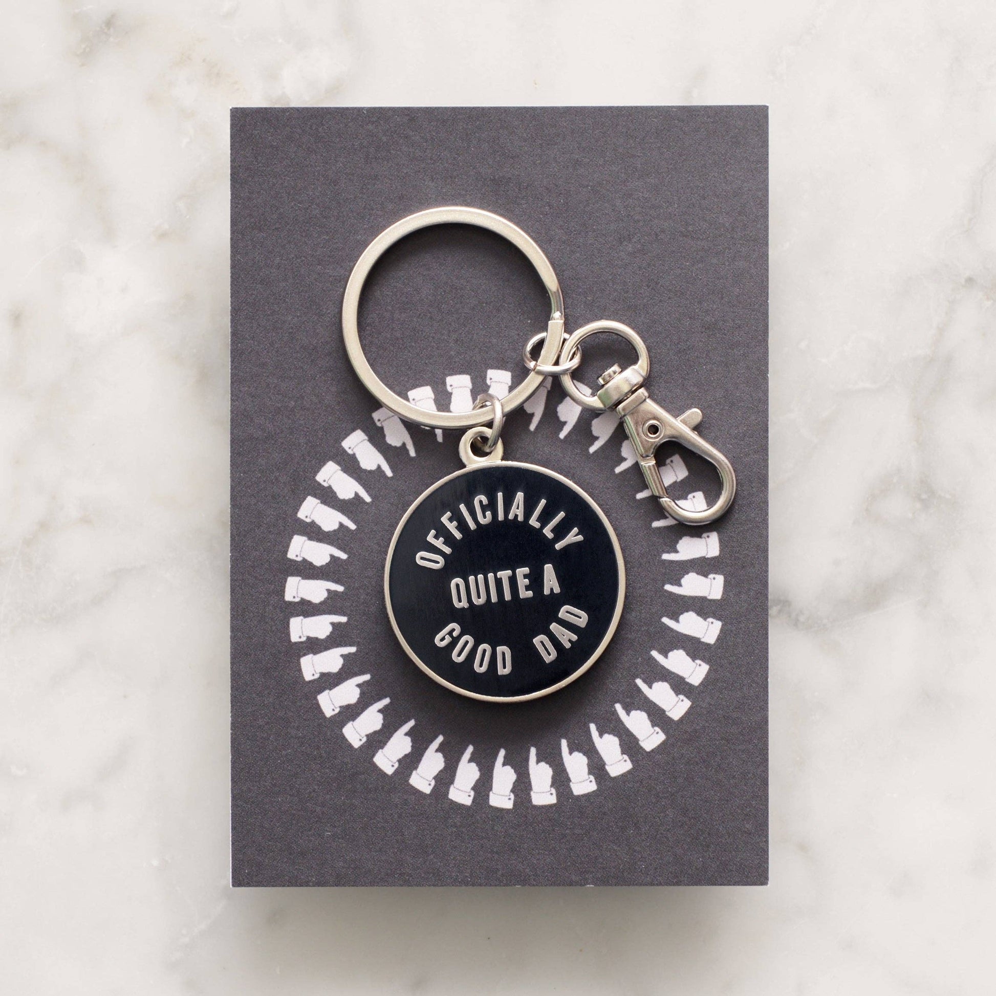Keychain with 'Officially Quite a Good Dad' text on a gray card with white illustrations, on a light gray background.