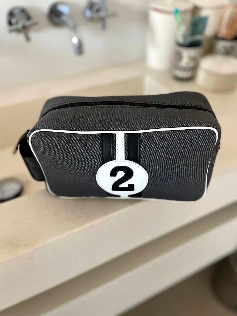 Black toiletry bag with a white stripe and number '2' on a bathroom counter.