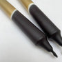 Two black markers with gold and black accents on a white background