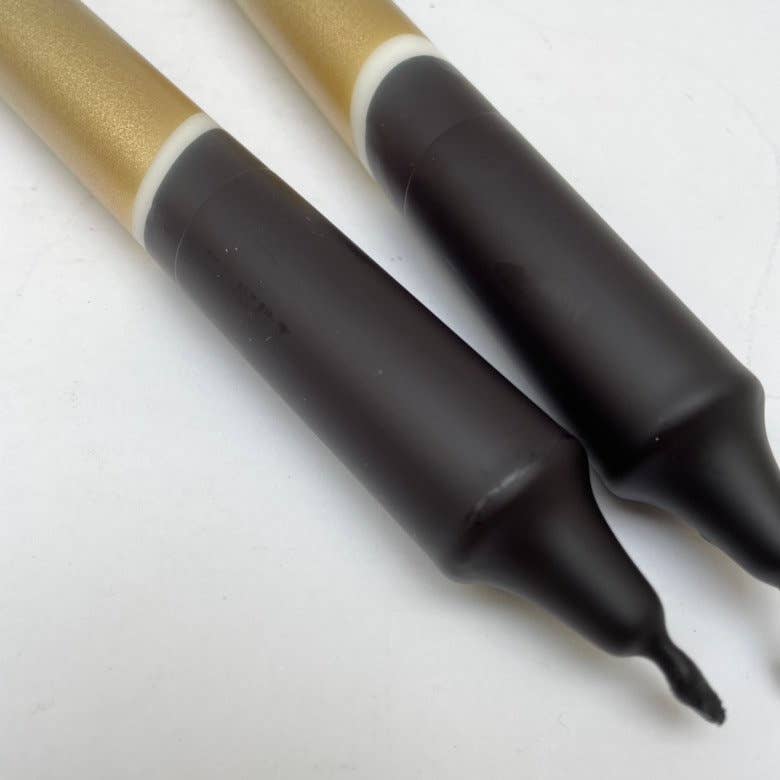 Two black markers with gold and black accents on a white background