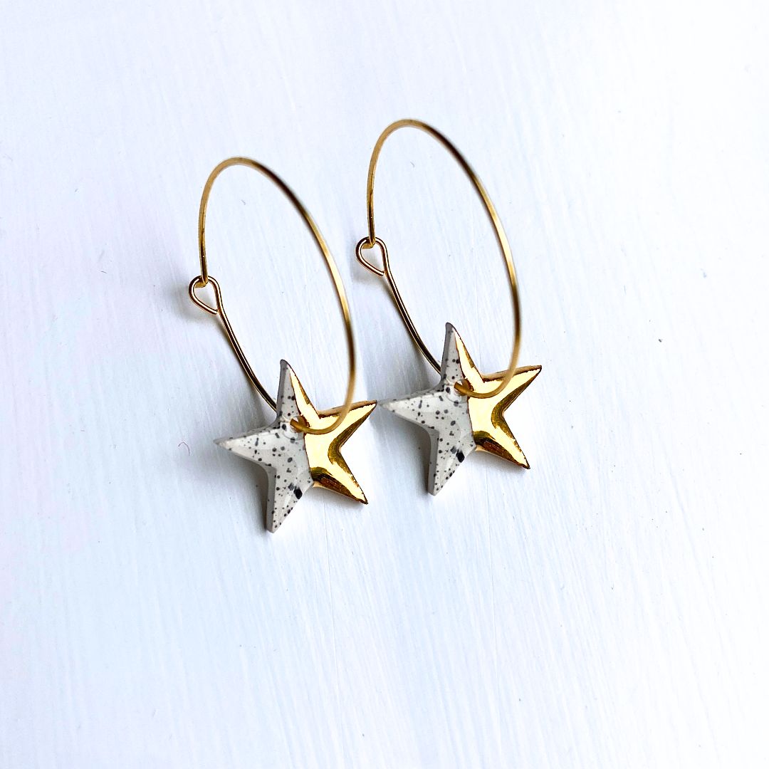 Star-shaped earrings with gold and white speckled design on a light background