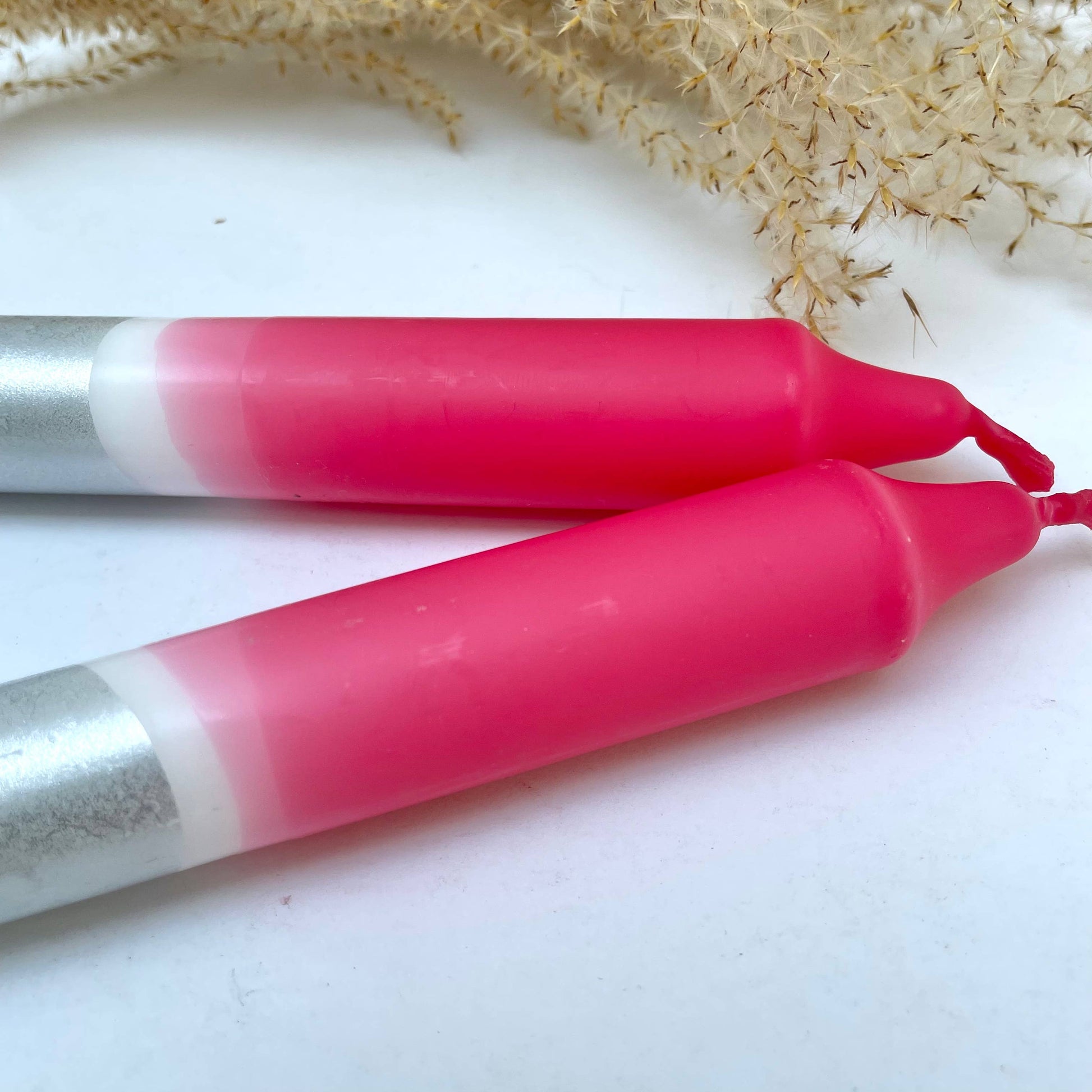 Two pink and silver jump ropes on a white surface with a natural background.