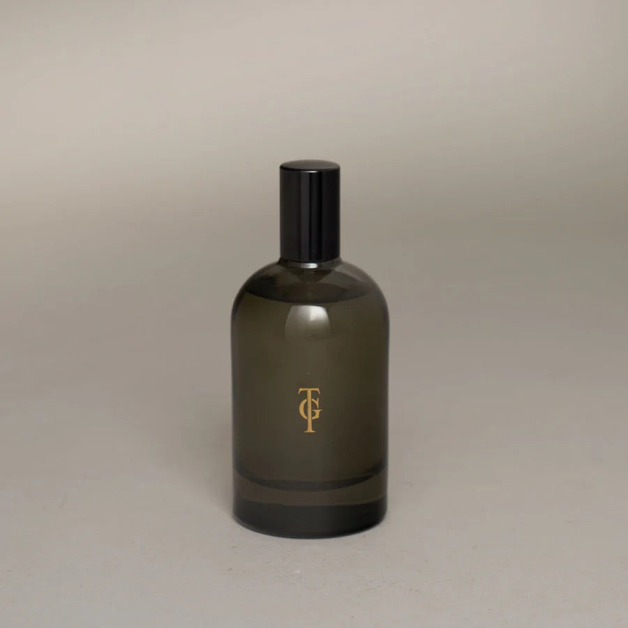 Dark glass bottle with gold logo on a beige background