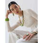 Woman wearing a long necklace with green accents against a white background
