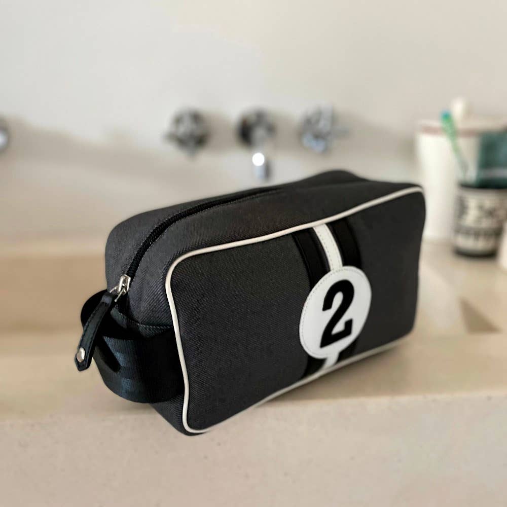 Black toiletry bag with a white number '2' on a bathroom counter