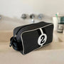 Black toiletry bag with a white number '2' on a bathroom counter