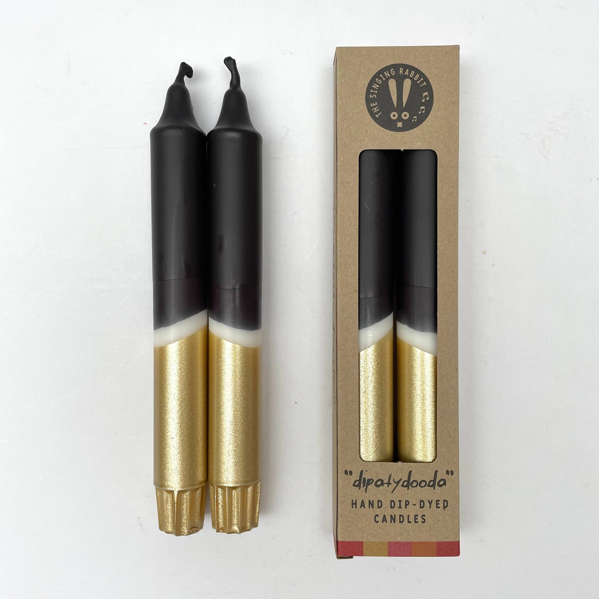 Two black and gold candles with a cardboard box on a white background