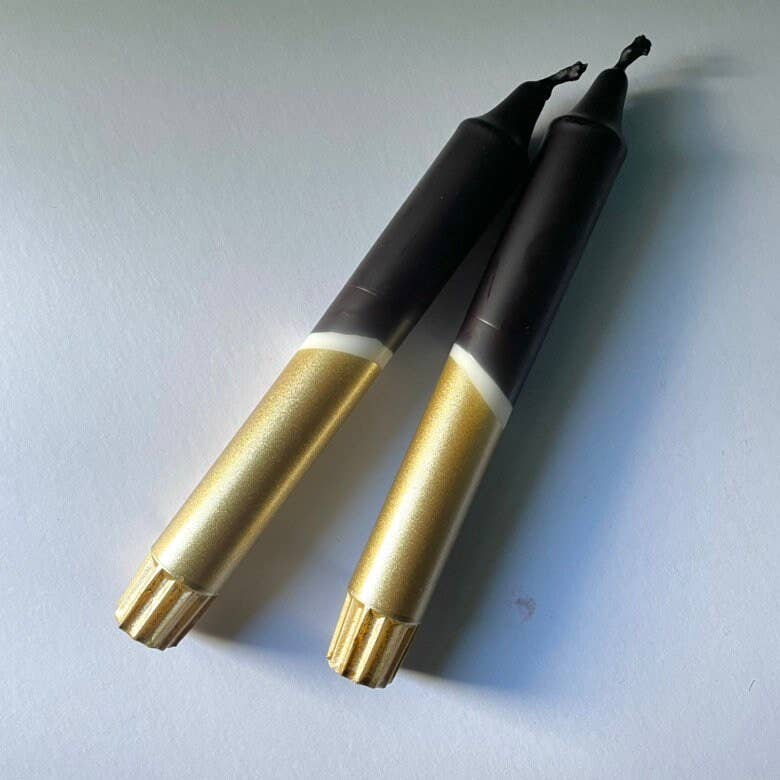 Two gold and black pens lying on a light blue surface