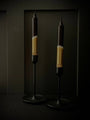 Two candle holders with black and gold design on a dark background