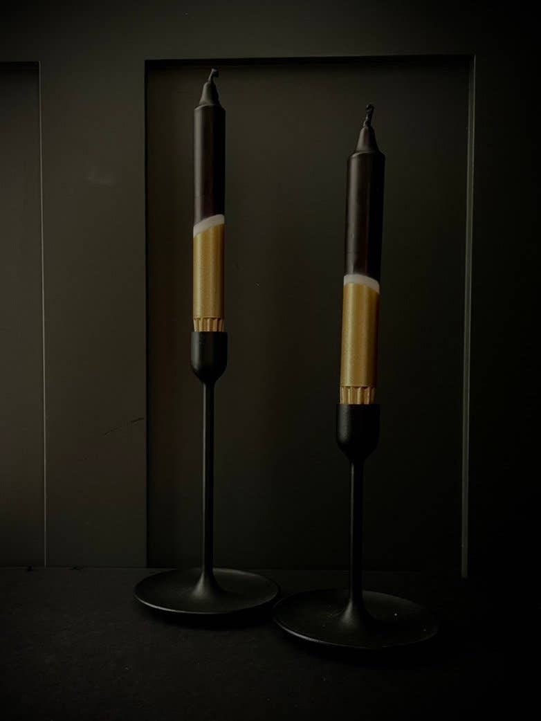 Two candle holders with black and gold design on a dark background